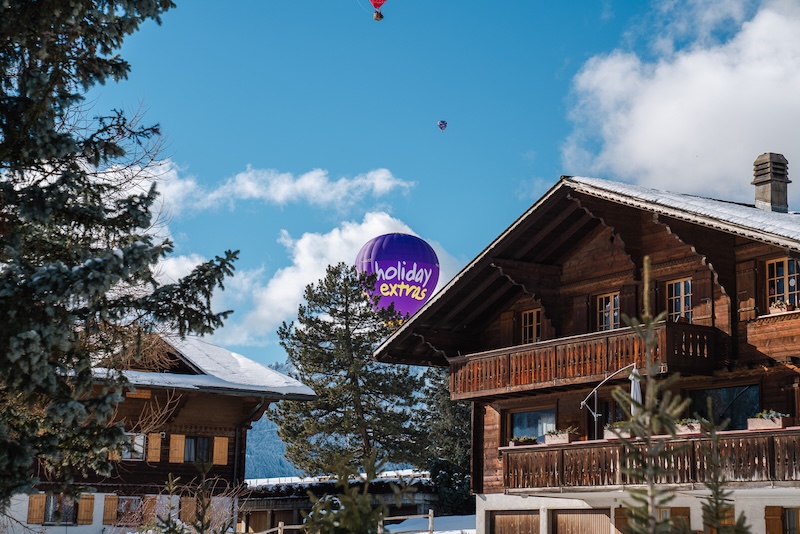 Switzerland in the snow with the Holiday Extras brand balloon rising in the background.